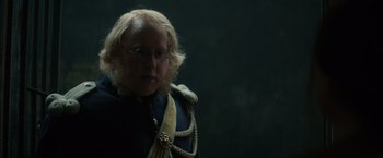 Movie still from “In Secret” (2013), directed by Charlie Stratton – A man with blonde hair and glasses wearing a uniform; Close Up shot, Over the shoulder angle