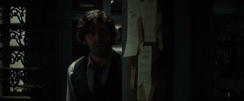 Movie still from “In Secret” (2013), directed by Charlie Stratton – A man standing in front of a wall covered with papers; Close Up shot, Over the shoulder angle