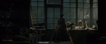 Movie still from “In Secret” (2013), directed by Charlie Stratton – A woman standing in front of a large window; Wide shot, Over the shoulder angle