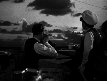 Movie still from “In Which We Serve” (1942), directed by Noël Coward – Two men are sitting at a table and one is talking on a cell phone; Medium shot, Over the shoulder angle