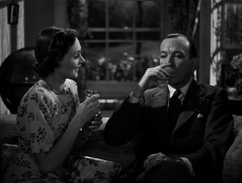 Movie still from “In Which We Serve” (1942), directed by Noël Coward – A man and a woman sitting on a couch; Medium shot, High angle