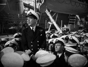 Movie still from “In Which We Serve” (1942), directed by Noël Coward – An old photo of a man in a navy uniform; Medium shot, Over the shoulder angle