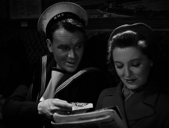 Movie still from “In Which We Serve” (1942), directed by Noël Coward – A man and a woman looking at something in a box; Medium shot, High angle