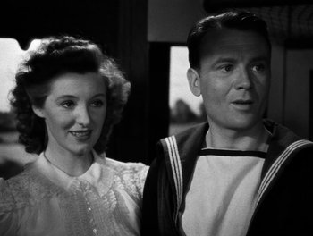 Movie still from “In Which We Serve” (1942), directed by Noël Coward – An old photo of a man and a woman standing next to each other; Medium shot, Low angle