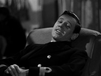 Movie still from “In Which We Serve” (1942), directed by Noël Coward – A black and white photo of a man sitting in a chair; Close Up shot, High angle