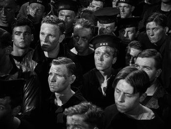 Movie still from “In Which We Serve” (1942), directed by Noël Coward – Black and white photograph of a group of men in hats; Medium shot, High angle