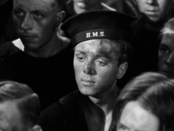 Movie still from “In Which We Serve” (1942), directed by Noël Coward – Black and white photograph of a man in a crowd; Close Up shot, High angle