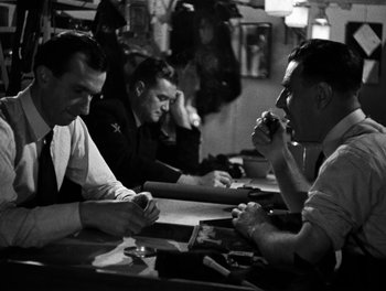 Movie still from “In Which We Serve” (1942), directed by Noël Coward – A group of men sitting at a table in a restaurant; Medium shot, Over the shoulder angle