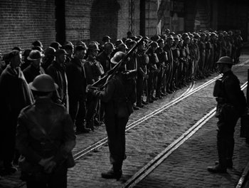 Movie still from “In Which We Serve” (1942), directed by Noël Coward – A black - and - white photo of a group of men standing next to each other; Wide shot, High angle
