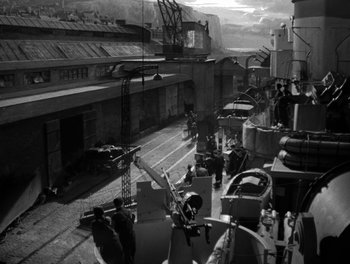 Movie still from “In Which We Serve” (1942), directed by Noël Coward – A black - and - white photo of a train station; Extreme Wide shot, High angle