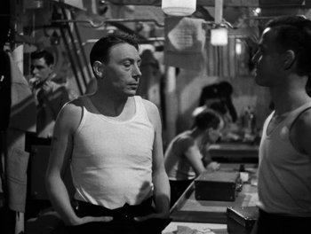 Movie still from “In Which We Serve” (1942), directed by Noël Coward – A black and white photo of a man talking to another man; Medium shot, Over the shoulder angle