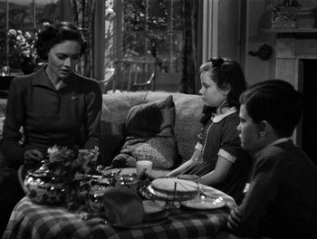 Movie still from “In Which We Serve” (1942), directed by Noël Coward – A family sitting at a table with a plate of food; Medium shot, High angle