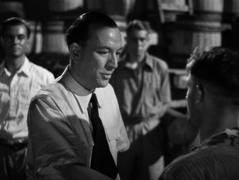 Movie still from “In Which We Serve” (1942), directed by Noël Coward – Black and white photograph of a man shaking hands; Medium shot, Over the shoulder angle