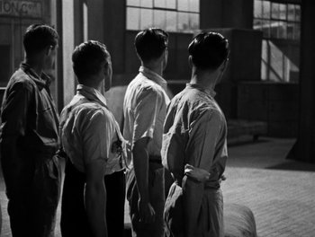 Movie still from “In Which We Serve” (1942), directed by Noël Coward – A black and white photo of a group of men standing; Medium shot, Low angle