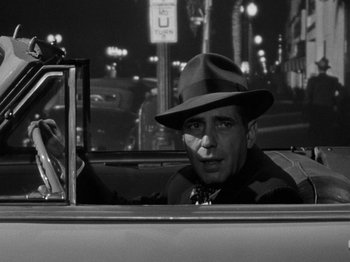 Movie still from “In a Lonely Place” (1950), directed by Nicholas Ray – A black and white photo of a man in a car; Close Up shot, Over the shoulder angle