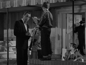 Movie still from “In a Lonely Place” (1950), directed by Nicholas Ray – A black and white photo of a man and a boy; Medium shot, Over the shoulder angle