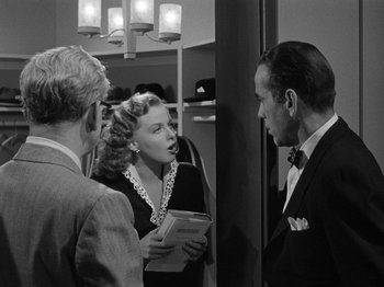 Movie still from “In a Lonely Place” (1950), directed by Nicholas Ray – A group of people standing next to each other in a room; Medium shot, Over the shoulder angle