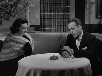 Movie still from “In a Lonely Place” (1950), directed by Nicholas Ray – A man and a woman sitting at a dinner table; Medium shot, High angle