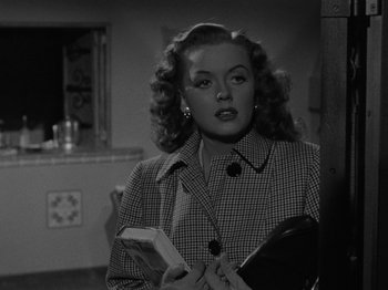 Movie still from “In a Lonely Place” (1950), directed by Nicholas Ray – A black - and - white photo of a woman holding a book; Medium shot, Low angle