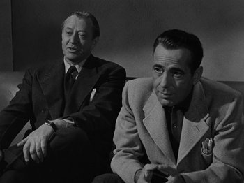 Movie still from “In a Lonely Place” (1950), directed by Nicholas Ray – A black and white photo of two men in suits; Medium shot, Over the shoulder angle