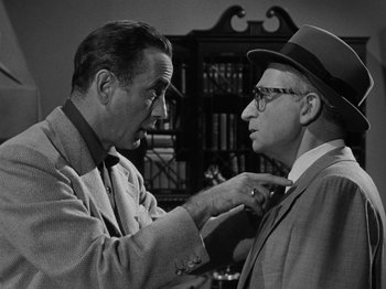 Movie still from “In a Lonely Place” (1950), directed by Nicholas Ray – A man fixing another man's tie in black and white photo; Medium shot, Over the shoulder angle