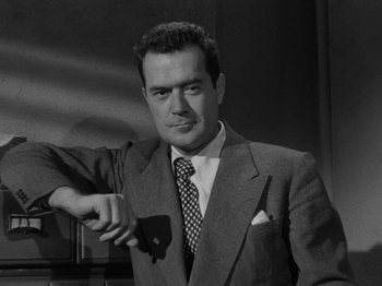 Movie still from “In a Lonely Place” (1950), directed by Nicholas Ray – A black and white photo of a man holding a cell phone; Medium shot, Low angle