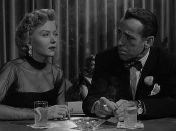 Movie still from “In a Lonely Place” (1950), directed by Nicholas Ray – A man and a woman sitting at a dinner table; Medium shot, Over the shoulder angle
