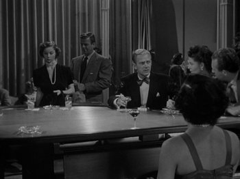 Movie still from “In a Lonely Place” (1950), directed by Nicholas Ray – A group of people sitting around a table; Wide shot, High angle