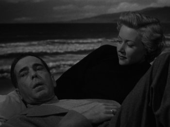 Movie still from “In a Lonely Place” (1950), directed by Nicholas Ray – A man and a woman on the beach; Medium shot, High angle
