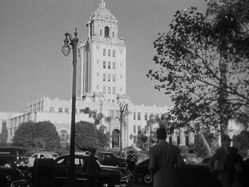 Movie still from “In a Lonely Place” (1950), directed by Nicholas Ray – A black - and - white photo of a building with a clock tower; Extreme Wide shot, Low angle