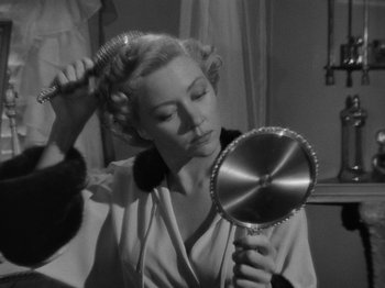 Movie still from “In a Lonely Place” (1950), directed by Nicholas Ray – A black and white photo of a woman brushing her hair; Close Up shot, High angle