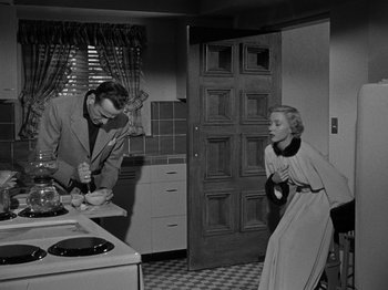 Movie still from “In a Lonely Place” (1950), directed by Nicholas Ray – A man and a woman in a kitchen; Medium shot, High angle