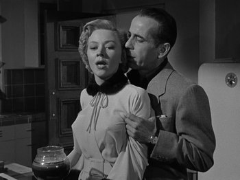 Movie still from “In a Lonely Place” (1950), directed by Nicholas Ray – A man and a woman are standing together in a kitchen; Medium shot, Low angle