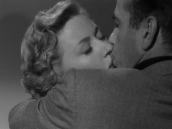 Movie still from “In a Lonely Place” (1950), directed by Nicholas Ray – A man and a woman kissing on a couch; Close Up shot, Low angle
