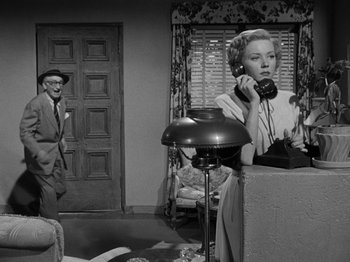 Movie still from “In a Lonely Place” (1950), directed by Nicholas Ray – An older woman talking on the phone in a living room; Medium shot, Low angle