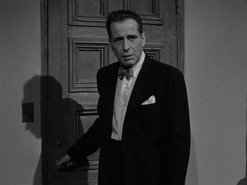 Movie still from “In a Lonely Place” (1950), directed by Nicholas Ray – A black and white photo of a man in a suit; Medium shot, Low angle