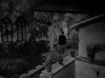 Movie still from “In a Lonely Place” (1950), directed by Nicholas Ray – A black and white photo of a man standing in a garden; Extreme Wide shot, High angle