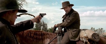 Movie still from “In a Valley of Violence” (2016), directed by Ti West – A man on a horse with a gun pointed at him; Medium shot, Over the shoulder angle