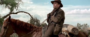 Movie still from “In a Valley of Violence” (2016), directed by Ti West – A man riding on the back of a brown horse; Medium shot, Low angle