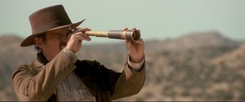 Movie still from “In a Valley of Violence” (2016), directed by Ti West – A man holding a telescope up to the sky; Close Up shot, Low angle