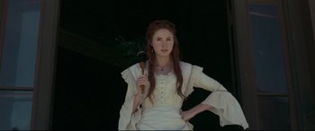 Movie still from “In a Valley of Violence” (2016), directed by Ti West – A woman in white dress holding a wooden spoon; Medium shot, Low angle