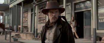 Movie still from “In a Valley of Violence” (2016), directed by Ti West – A man wearing a brown hat and a brown jacket; Medium shot, Over the shoulder angle
