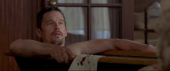 Movie still from “In a Valley of Violence” (2016), directed by Ti West – A person sitting on a chair; Close Up shot, Low angle
