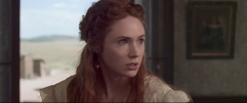 Movie still from “In a Valley of Violence” (2016), directed by Ti West – A person with long red hair; Close Up shot, Over the shoulder angle