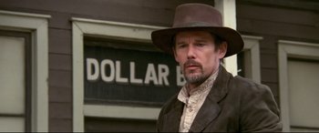 Movie still from “In a Valley of Violence” (2016), directed by Ti West – A man wearing a brown hat and a brown jacket; Close Up shot, Low angle