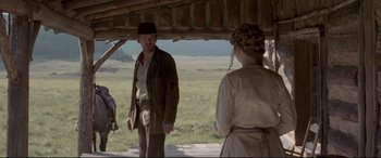 Movie still from “In a Valley of Violence” (2016), directed by Ti West – A man and a woman standing next to each other in front of an open barn; Wide shot, Over the shoulder angle