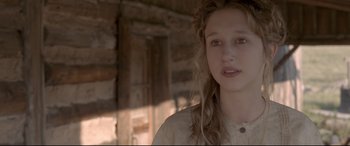 Movie still from “In a Valley of Violence” (2016), directed by Ti West – A young woman with long blonde curly hair; Close Up shot, Over the shoulder angle