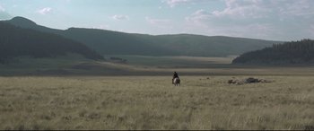 Movie still from “In a Valley of Violence” (2016), directed by Ti West – A man riding a horse through a field of tall grass; Extreme Wide shot, High angle