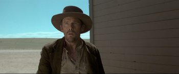 Movie still from “In a Valley of Violence” (2016), directed by Ti West – A man wearing a hat standing in front of a building; Medium shot, Low angle