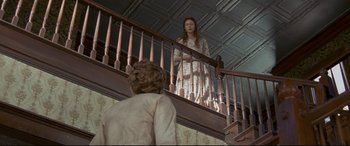 Movie still from “In a Valley of Violence” (2016), directed by Ti West – A woman standing on top of a wooden railing next to a person; Wide shot, Low angle